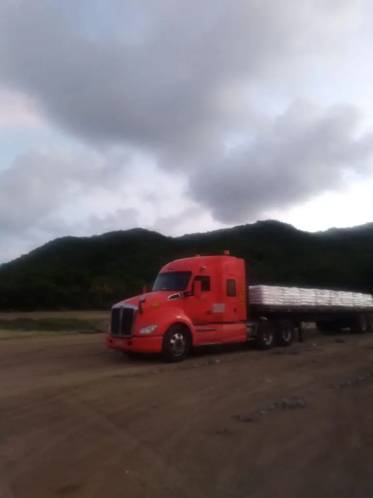 Tractocamión rojo de la operación AQL con plataforma cargada
